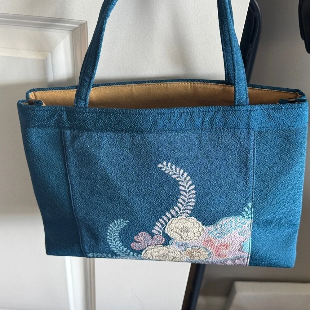 Teal-colored‎ handbag bag featuring intricate floral embroidery